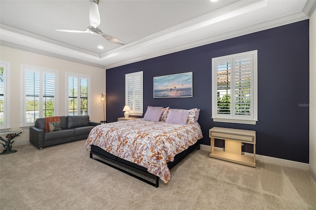 carpeted bedroom featuring a ceiling fan, baseboards, a tray ceiling, and crown molding