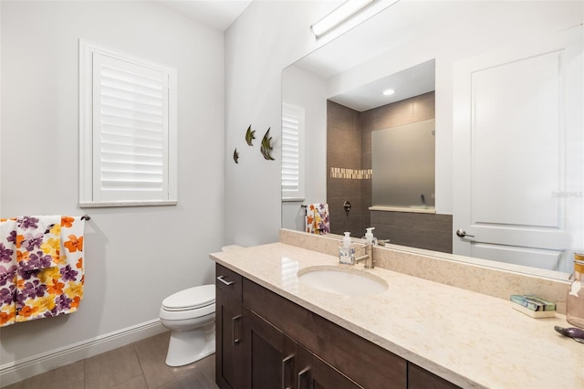 full bath featuring toilet, a tile shower, vanity, tile patterned flooring, and baseboards