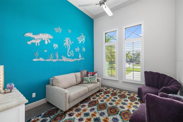 living area with a ceiling fan, crown molding, baseboards, and wood finished floors