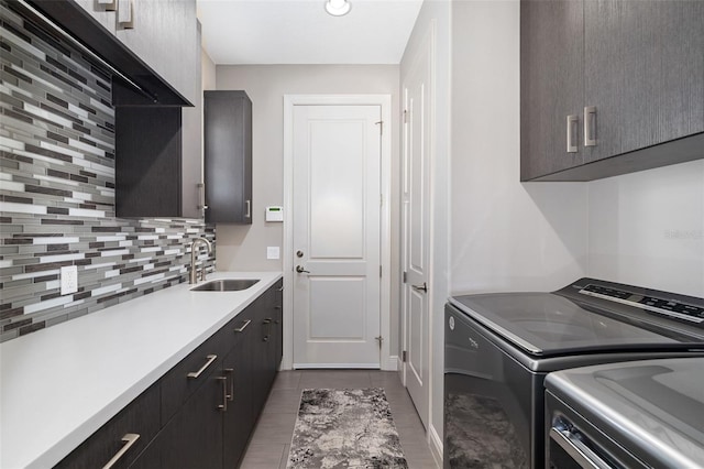 laundry room featuring cabinet space, light tile patterned flooring, a sink, and washing machine and clothes dryer