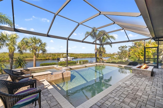 view of swimming pool with a patio, a lanai, a fire pit, a water view, and a pool with connected hot tub