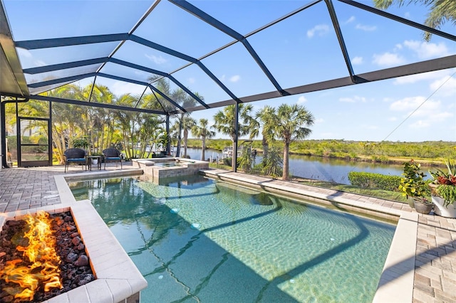 view of swimming pool featuring a pool with connected hot tub, glass enclosure, a water view, and a patio