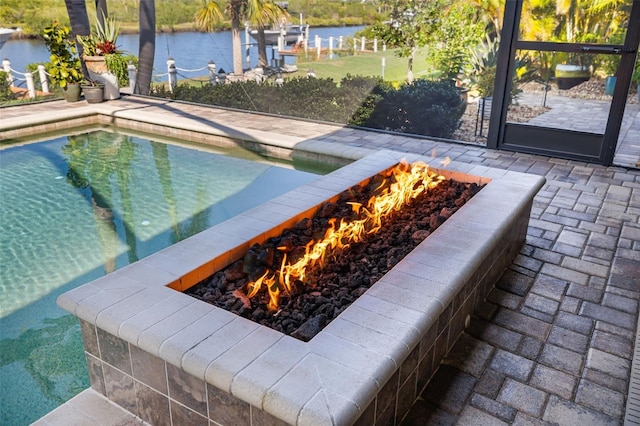 outdoor pool with a water view, an outdoor fire pit, and a patio