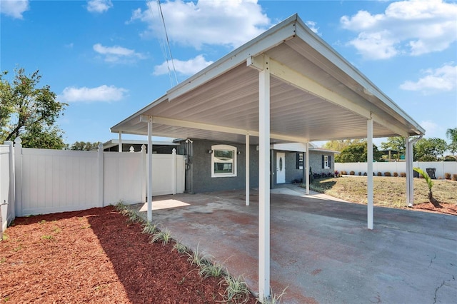 view of parking with a carport and fence