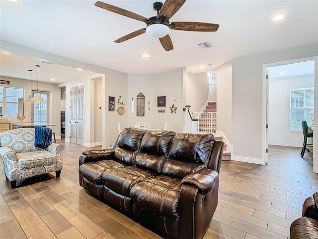 living area with recessed lighting, visible vents, plenty of natural light, and stairs