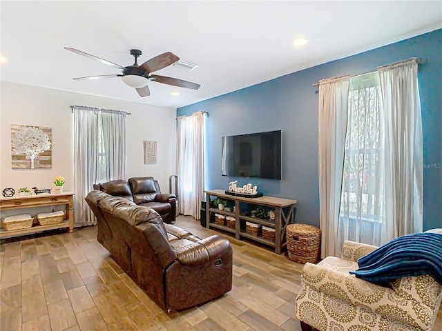 living area featuring ceiling fan, wood finished floors, visible vents, and a healthy amount of sunlight