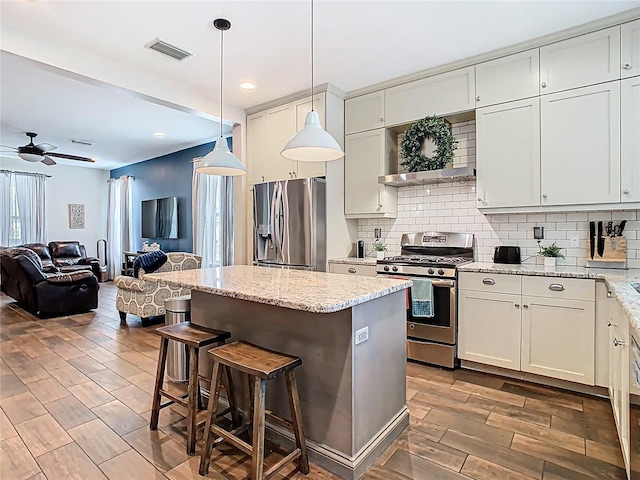 kitchen featuring backsplash, a center island, open floor plan, a kitchen bar, and appliances with stainless steel finishes