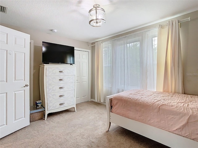 bedroom featuring visible vents, a chandelier, light colored carpet, a closet, and a textured ceiling