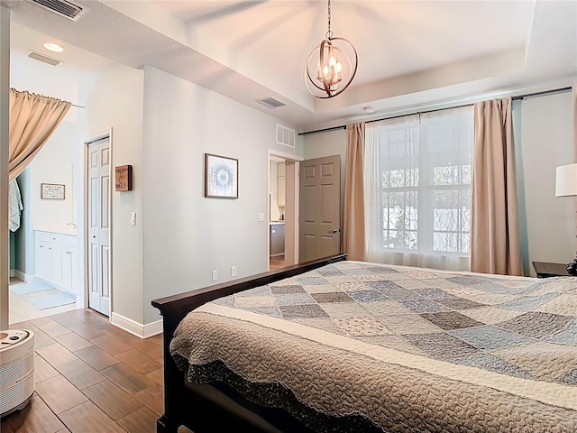 bedroom with a raised ceiling, visible vents, and wood tiled floor