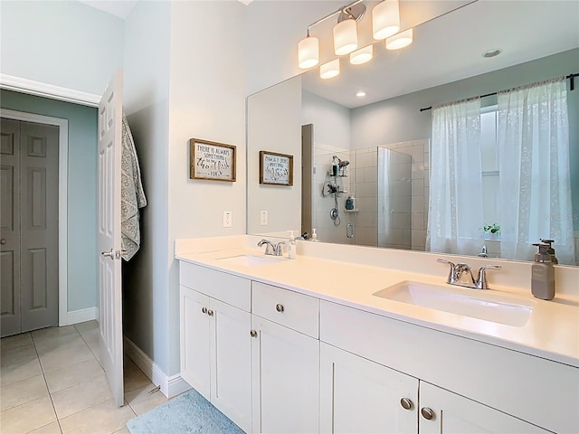 full bathroom with a tile shower, tile patterned flooring, double vanity, and a sink