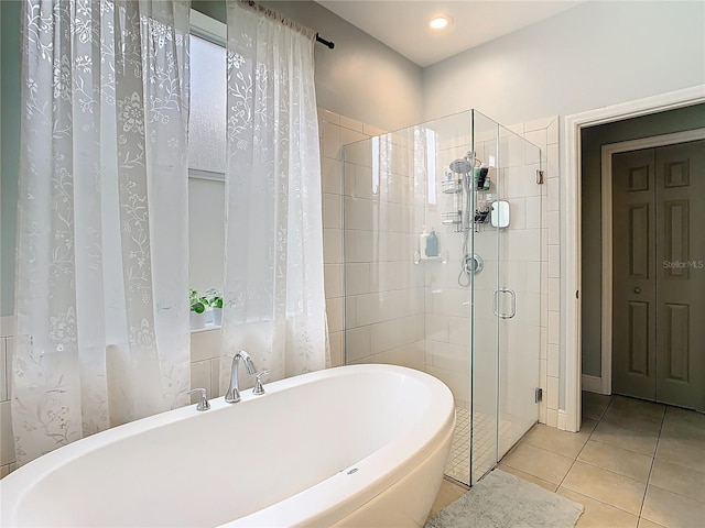 bathroom featuring tile patterned flooring, a stall shower, and a freestanding tub