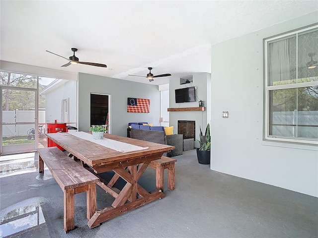 dining area featuring a fireplace, concrete floors, and ceiling fan