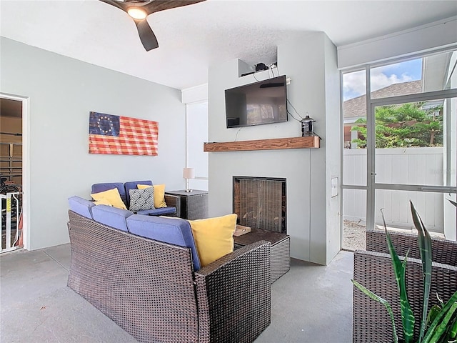 living room with a fireplace, concrete floors, and a ceiling fan