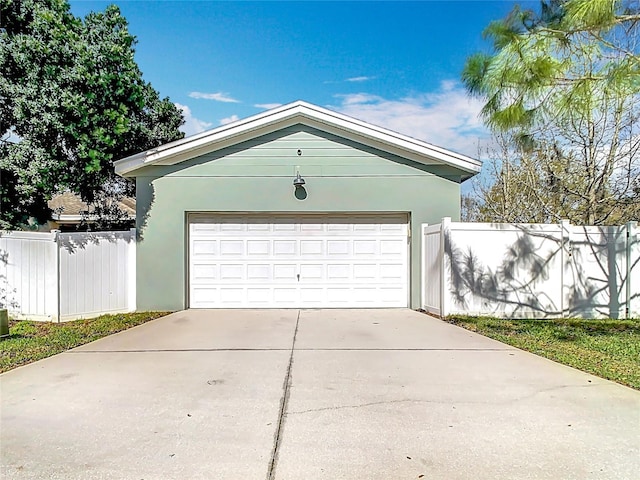 garage featuring driveway and fence