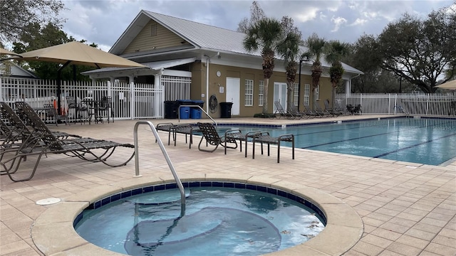 community pool featuring a patio area, fence, and a hot tub