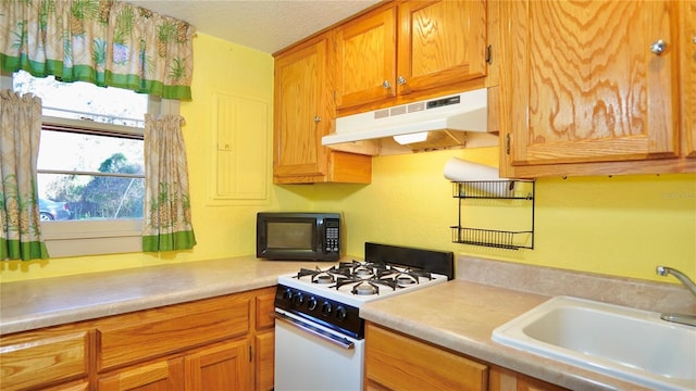 kitchen with black microwave, under cabinet range hood, a sink, light countertops, and white gas range oven