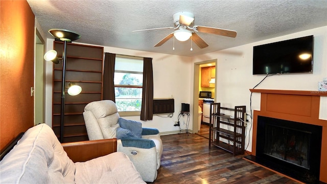 living area with dark wood-style flooring, a fireplace with raised hearth, and a textured ceiling