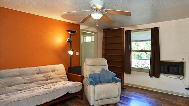 living area featuring dark wood-style floors, ceiling fan, a textured ceiling, and a glass covered fireplace