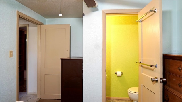 bathroom featuring a textured ceiling, tile patterned flooring, and toilet