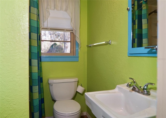 full bathroom with a textured wall, a sink, and toilet