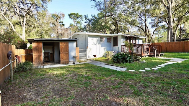 back of house featuring a lawn, a fenced backyard, and a wooden deck