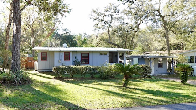 view of front of property featuring metal roof, board and batten siding, a front yard, and fence