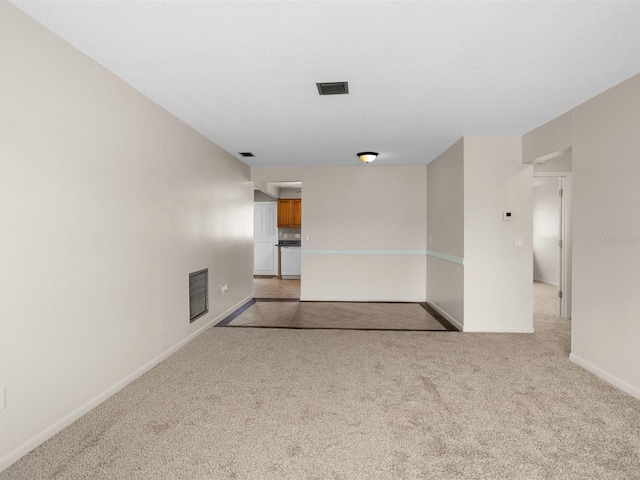 spare room featuring light carpet, visible vents, and baseboards