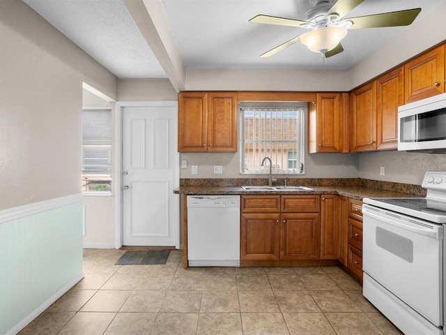 kitchen featuring white appliances, light tile patterned floors, brown cabinets, and a sink