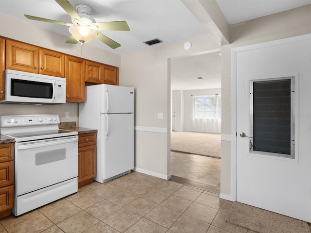 kitchen featuring light tile patterned floors, white appliances, visible vents, and brown cabinets