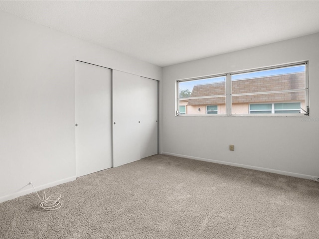 unfurnished bedroom featuring carpet floors, a textured ceiling, baseboards, and a closet