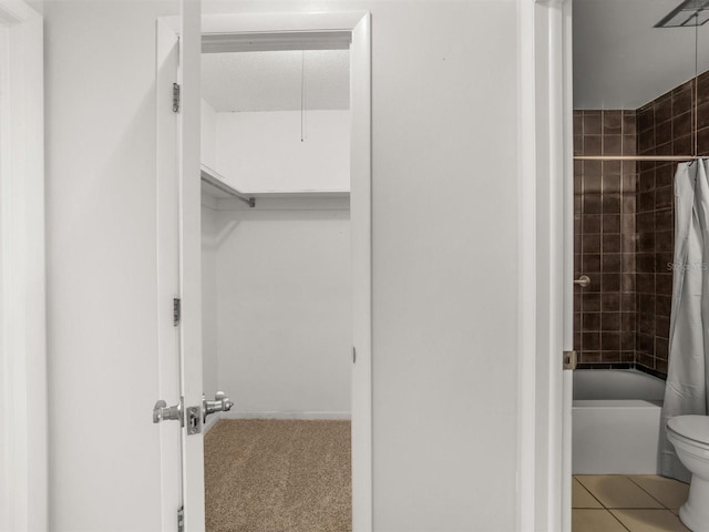 full bathroom featuring shower / bath combo, a spacious closet, toilet, and tile patterned floors