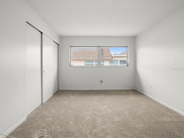 unfurnished bedroom with carpet floors, baseboards, and a closet