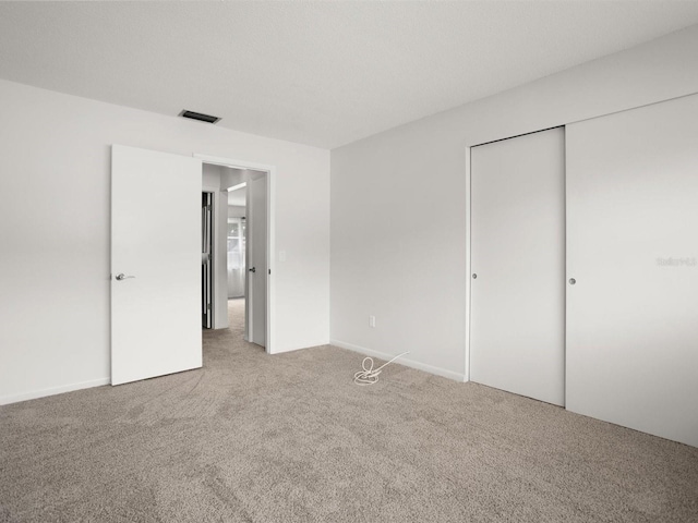 unfurnished bedroom with a textured ceiling, carpet floors, a closet, and visible vents