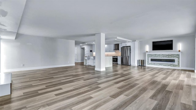 855 Bayway Blvd Unit 105, Clearwater, FL 33767 - unfurnished living room with light wood finished floors, baseboards, and a tile fireplace