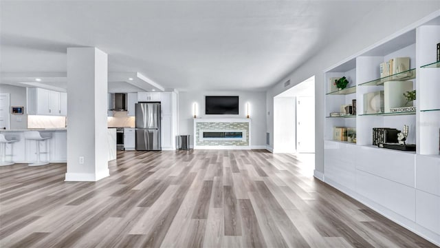 855 Bayway Blvd Unit 105, Clearwater, FL 33767 - unfurnished living room with light wood-type flooring, a fireplace, baseboards, and recessed lighting