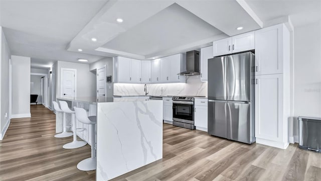 855 Bayway Blvd Unit 105, Clearwater, FL 33767 - kitchen featuring stainless steel appliances, wall chimney exhaust hood, recessed lighting, white cabinets, and light wood-style floors