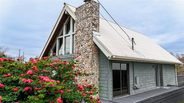 view of home's exterior with metal roof, a chimney, and a wooden deck