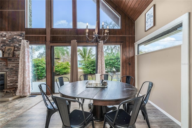 dining room featuring high vaulted ceiling, baseboards, a chandelier, and wood finished floors