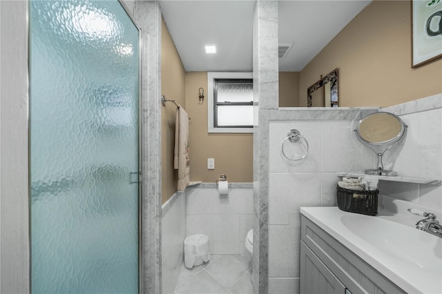 full bath with a stall shower, visible vents, toilet, vanity, and tile walls