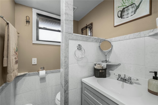 half bath featuring toilet, tile walls, and vanity