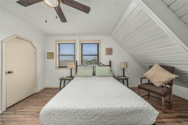 bedroom featuring a textured ceiling, lofted ceiling, wood finished floors, a ceiling fan, and baseboards