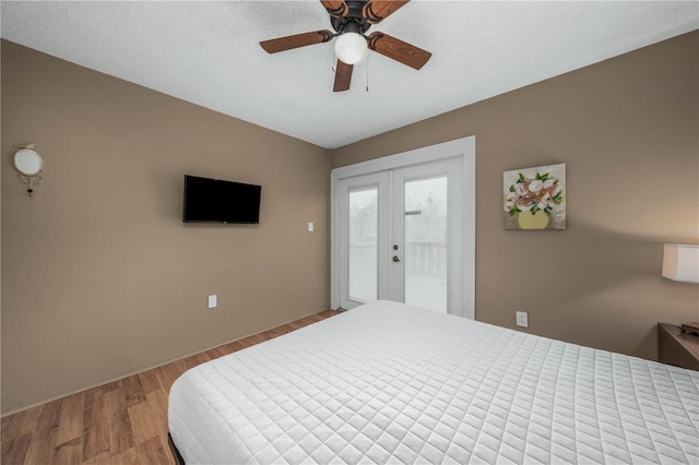 bedroom featuring a textured ceiling, wood finished floors, a ceiling fan, access to outside, and french doors