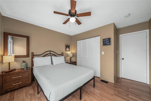 bedroom with light wood finished floors, ceiling fan, visible vents, and a closet