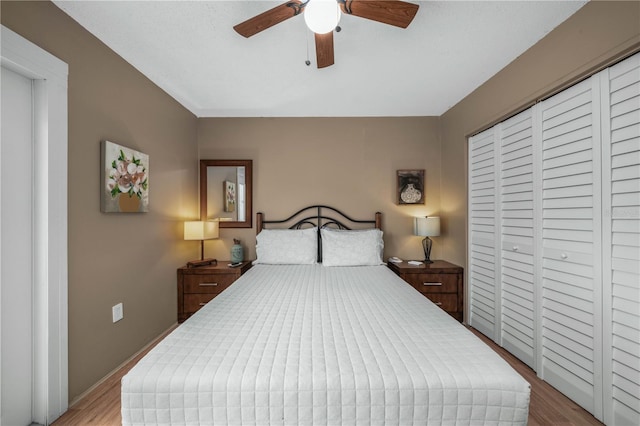 bedroom featuring a ceiling fan, a closet, baseboards, and wood finished floors