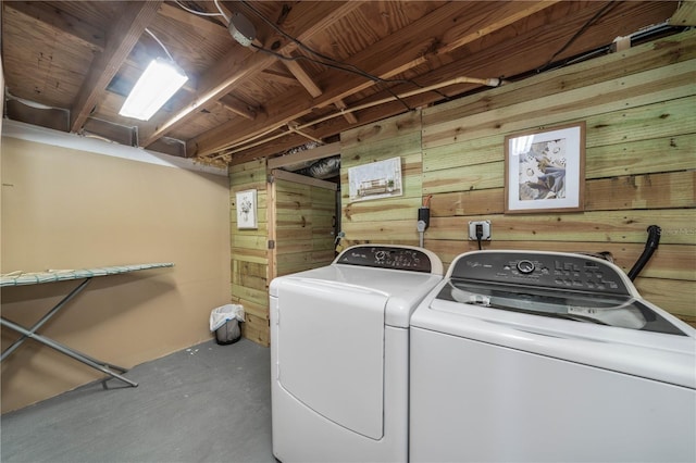 clothes washing area with laundry area, wood walls, and washing machine and clothes dryer