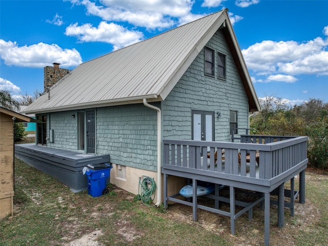 rear view of property with a standing seam roof, a chimney, metal roof, and a wooden deck