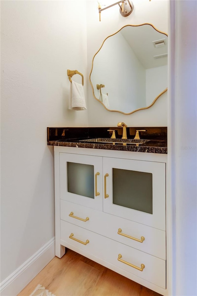 bathroom with visible vents, wood finished floors, vanity, and baseboards