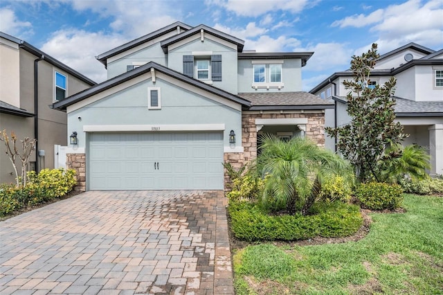 craftsman-style home with a garage, stone siding, decorative driveway, and stucco siding