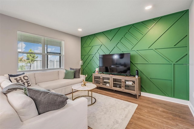 living area with an accent wall, recessed lighting, baseboards, and wood finished floors