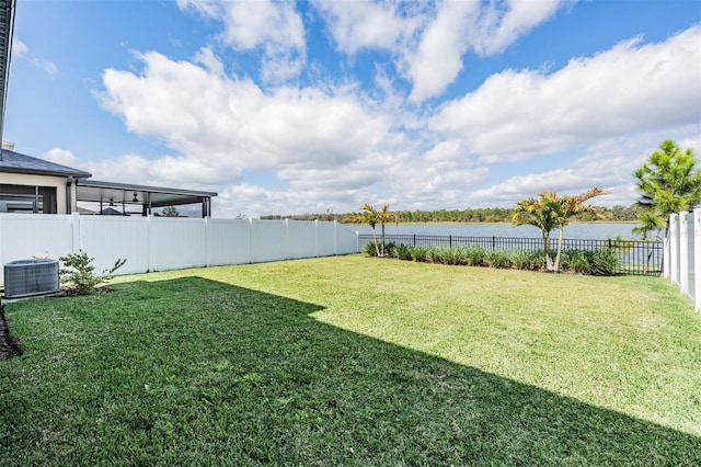 view of yard with a water view, a fenced backyard, and central air condition unit